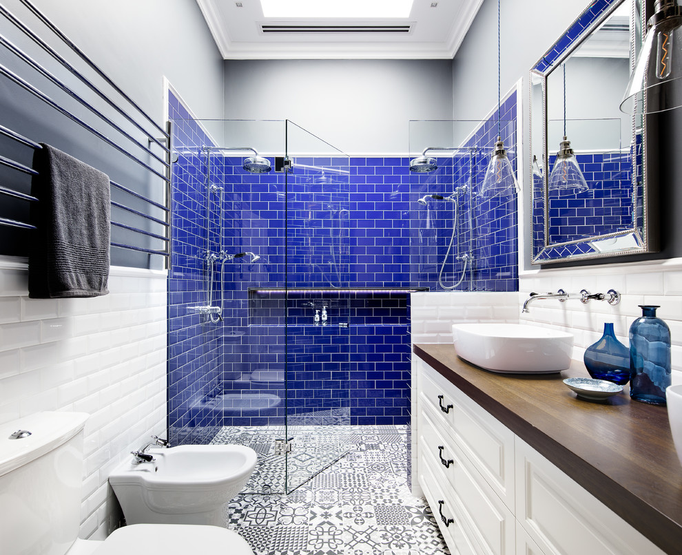 This is an example of a transitional 3/4 bathroom in Melbourne with raised-panel cabinets, white cabinets, a double shower, a two-piece toilet, blue tile, white tile, black walls, ceramic floors, a vessel sink, wood benchtops and a hinged shower door.