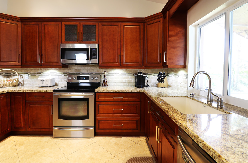 Mid-sized transitional u-shaped porcelain tile eat-in kitchen photo in Miami with an undermount sink, raised-panel cabinets, medium tone wood cabinets, granite countertops, beige backsplash, mosaic tile backsplash, stainless steel appliances and no island