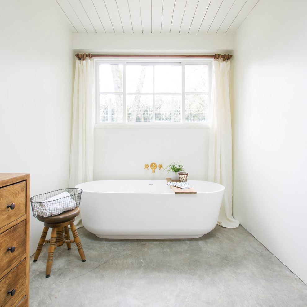 Inspiration for a mid-sized country master bathroom in San Francisco with medium wood cabinets, a freestanding tub, white walls, concrete floors, wood benchtops, grey floor and flat-panel cabinets.