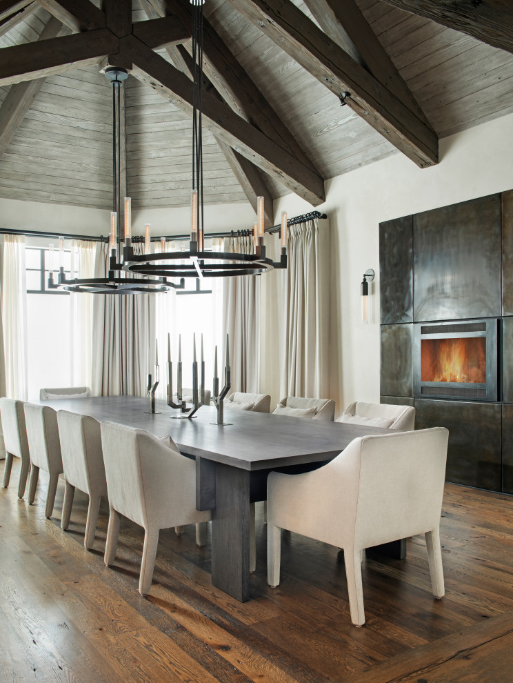 Project Shades of Grey - Example of a large trendy medium tone wood floor, brown floor, exposed beam, vaulted ceiling and wood ceiling enclosed dining room design with white walls, a standard fireplace and a metal fireplace