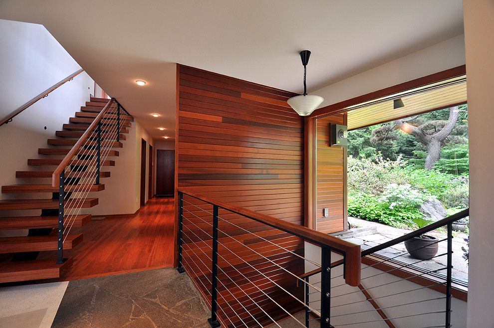 This is an example of a mid-sized contemporary wood floating staircase in Seattle with open risers and cable railing.