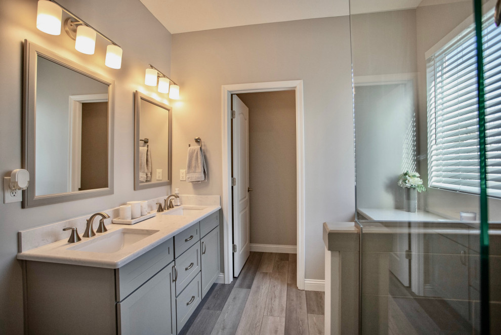 Inspiration for a medium sized classic ensuite bathroom in Cincinnati with shaker cabinets, grey cabinets, a corner shower, a two-piece toilet, grey tiles, ceramic tiles, beige walls, vinyl flooring, a submerged sink, engineered stone worktops, grey floors, a hinged door, white worktops, a shower bench, double sinks and a built in vanity unit.