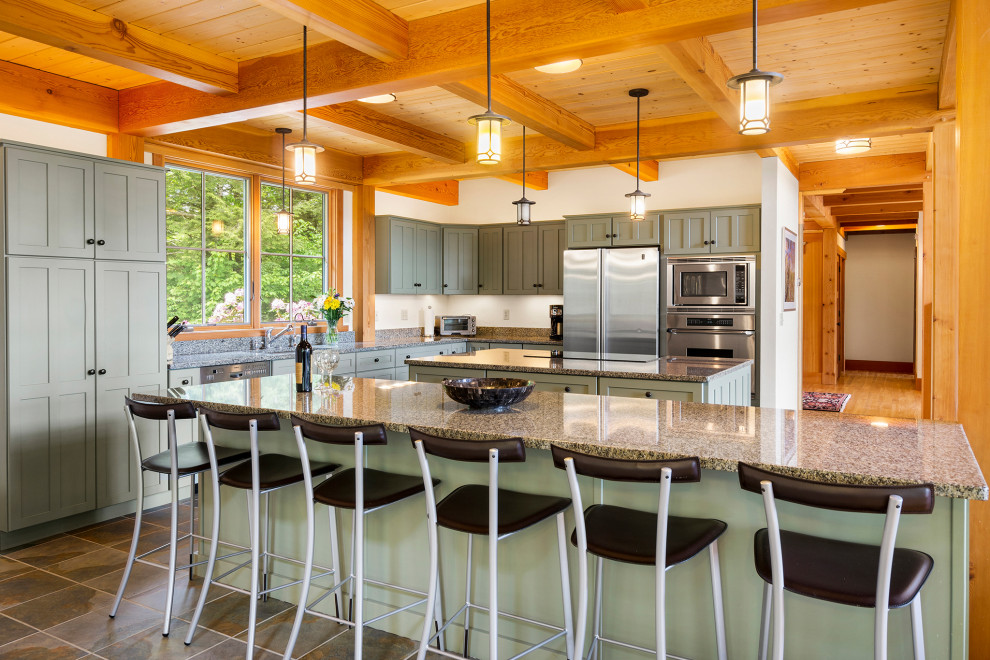 Inspiration for a large arts and crafts l-shaped open plan kitchen in Other with an undermount sink, shaker cabinets, green cabinets, granite benchtops, stainless steel appliances, slate floors, multiple islands, grey floor and exposed beam.