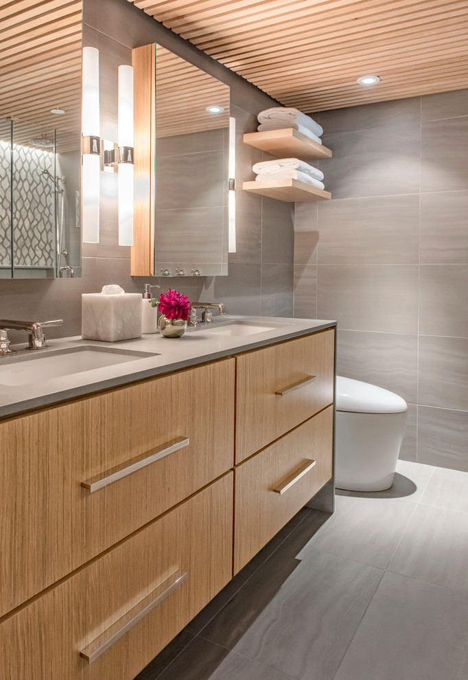 Example of a mid-sized trendy master gray tile and mosaic tile porcelain tile corner shower design in Vancouver with flat-panel cabinets, brown cabinets, an undermount tub, a two-piece toilet, beige walls, an undermount sink and wood countertops