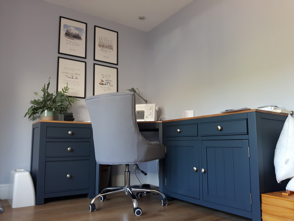 This is an example of a classic study in Other with blue walls, laminate floors and a freestanding desk.