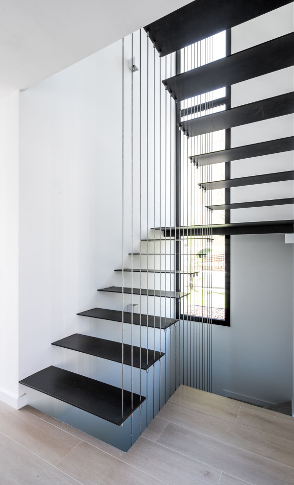 Diseño de escalera suspendida moderna de tamaño medio con barandilla de cable