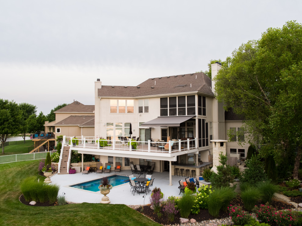 Ispirazione per un'ampia piscina monocorsia tradizionale rettangolare dietro casa con una vasca idromassaggio e lastre di cemento