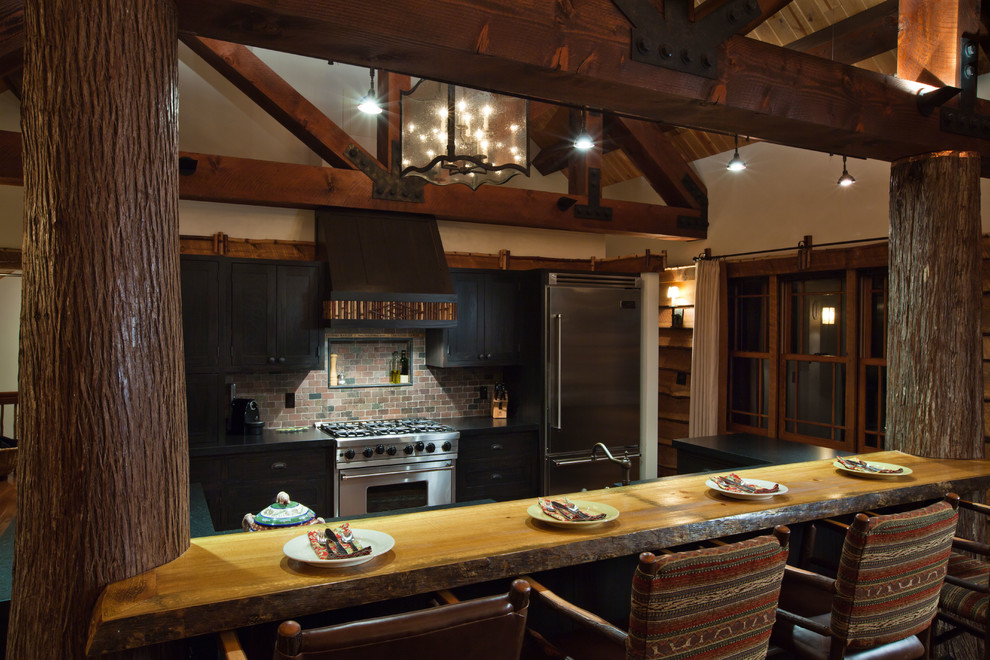 Open concept kitchen - mid-sized rustic u-shaped light wood floor open concept kitchen idea in Boston with flat-panel cabinets, light wood cabinets, soapstone countertops, terra-cotta backsplash, black appliances and a peninsula