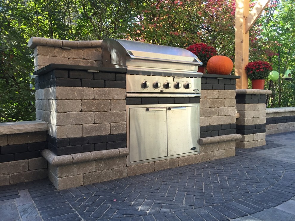 Photo of a mid-sized traditional backyard patio in Chicago with an outdoor kitchen, natural stone pavers and no cover.