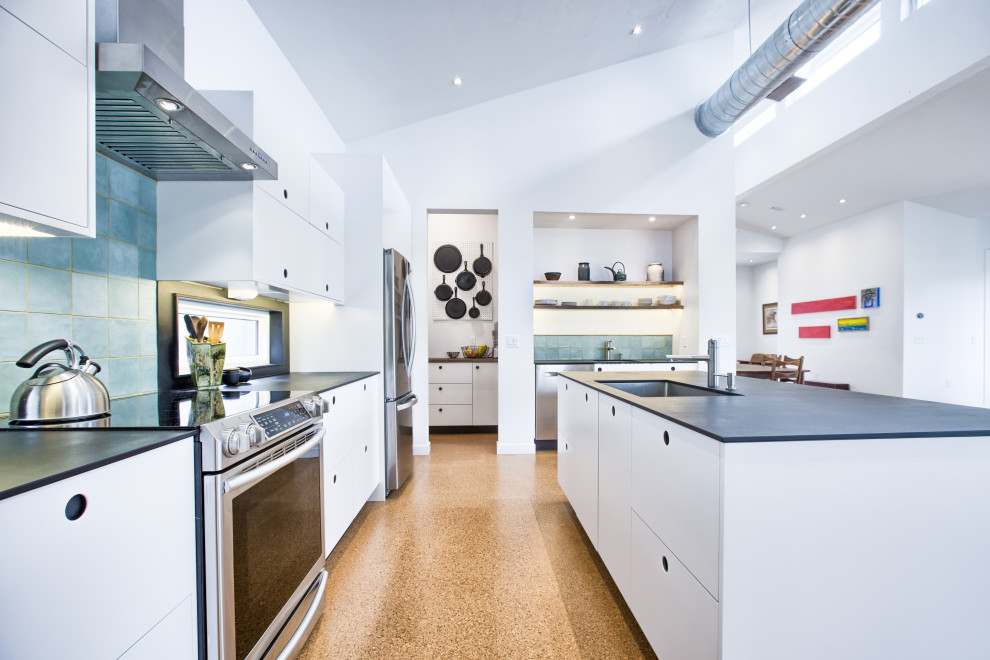 Mid-sized modern l-shaped kitchen in Jacksonville with a single-bowl sink, flat-panel cabinets, white cabinets, blue splashback, porcelain splashback, stainless steel appliances, cork floors and vaulted.