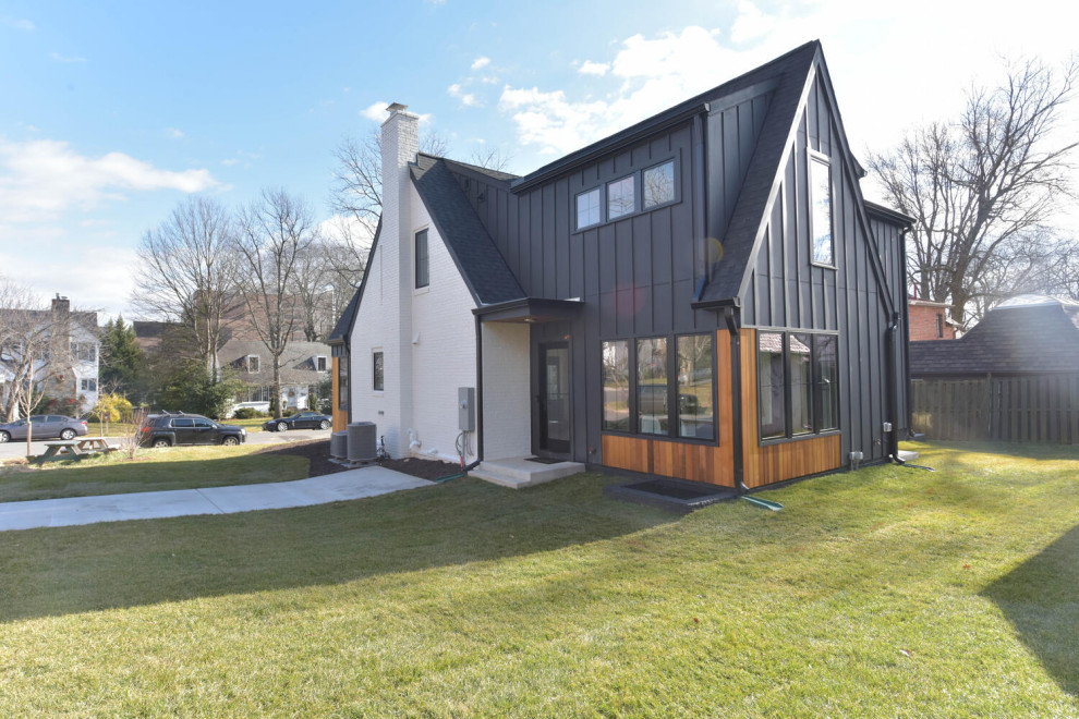 Cette photo montre une façade de maison noire tendance en planches et couvre-joints de taille moyenne et à un étage avec un revêtement mixte, un toit à deux pans, un toit mixte et un toit noir.