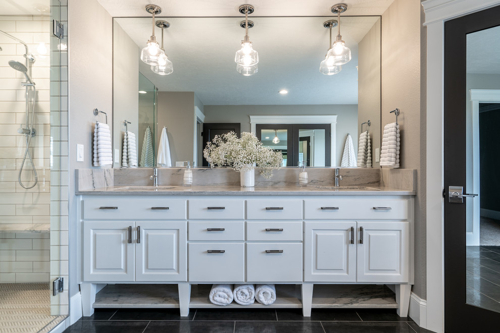 Freestanding bathtub - transitional master gray tile porcelain tile freestanding bathtub idea in Seattle with raised-panel cabinets, white cabinets, a two-piece toilet, gray walls, an undermount sink, quartz countertops, a hinged shower door and white countertops