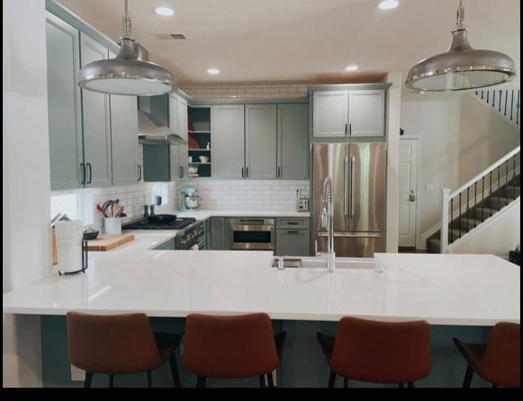 Idéer för att renovera ett litet vintage vit vitt kök, med en undermonterad diskho, luckor med infälld panel, gröna skåp, bänkskiva i kvarts, vitt stänkskydd, stänkskydd i keramik, rostfria vitvaror, laminatgolv, en köksö och brunt golv