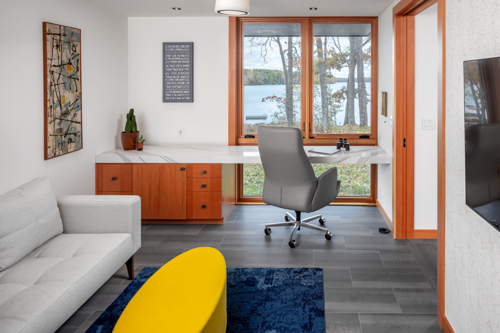 This is an example of a mid-sized country home office in Minneapolis with white walls, porcelain floors, a built-in desk, grey floor and wallpaper.