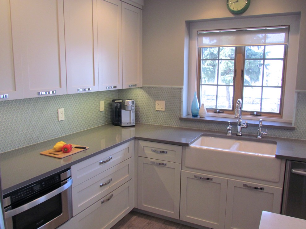 Example of a transitional l-shaped porcelain tile eat-in kitchen design in Chicago with a farmhouse sink, shaker cabinets, white cabinets, quartz countertops, blue backsplash, glass tile backsplash, stainless steel appliances and an island