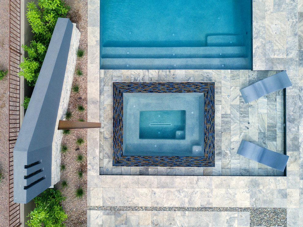 Mid-sized modern backyard rectangular infinity pool in Phoenix with natural stone pavers.