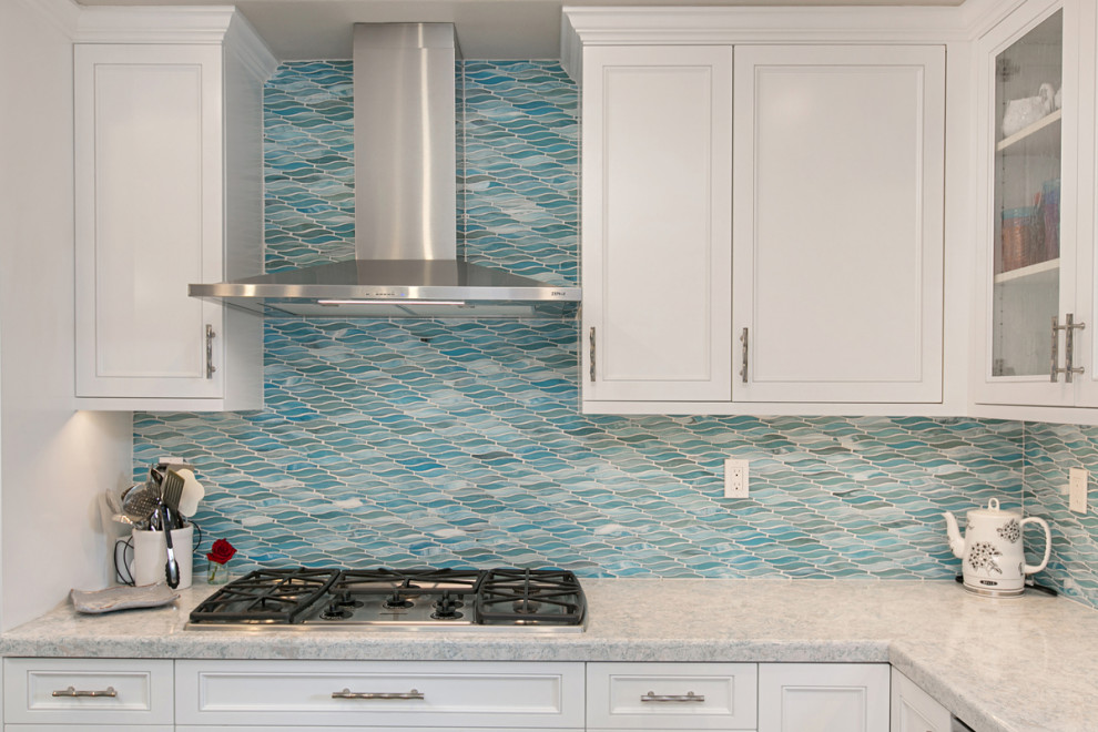 This is an example of a mid-sized contemporary l-shaped open plan kitchen in San Diego with an undermount sink, beaded inset cabinets, turquoise cabinets, quartzite benchtops, blue splashback, glass tile splashback, stainless steel appliances, light hardwood floors, with island, beige floor and white benchtop.