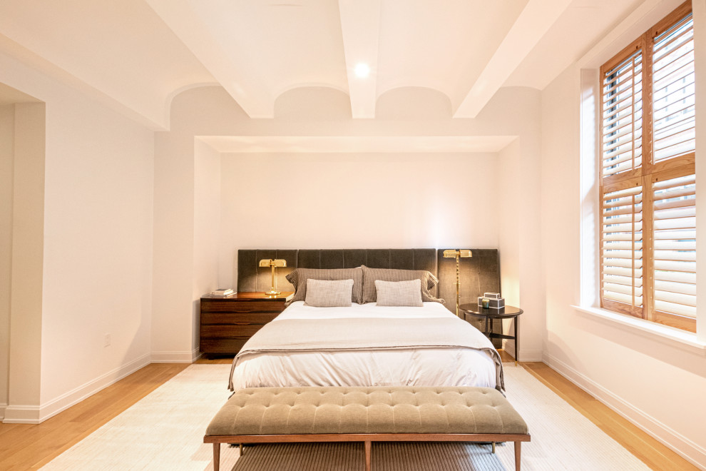 Пример оригинального дизайна: большая хозяйская спальня в стиле ретро с белыми стенами, паркетным полом среднего тона, коричневым полом и сводчатым потолком