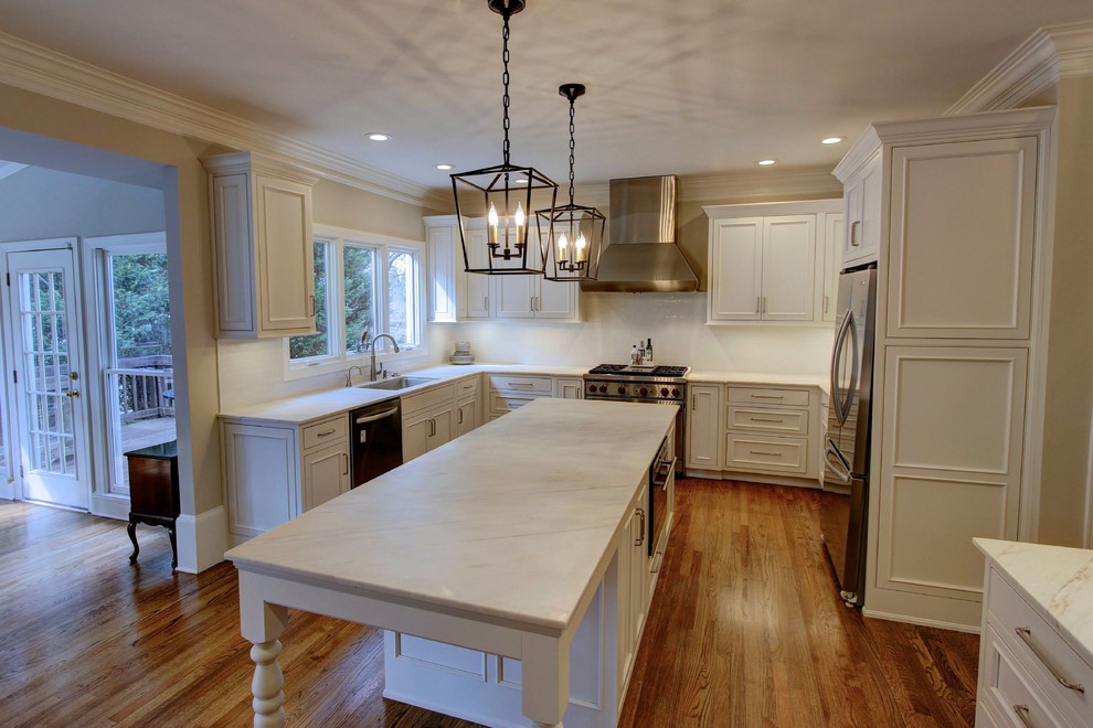 Example of a large transitional u-shaped light wood floor kitchen pantry design in Atlanta with an undermount sink, recessed-panel cabinets, white cabinets, quartz countertops, white backsplash, subway tile backsplash, stainless steel appliances and an island