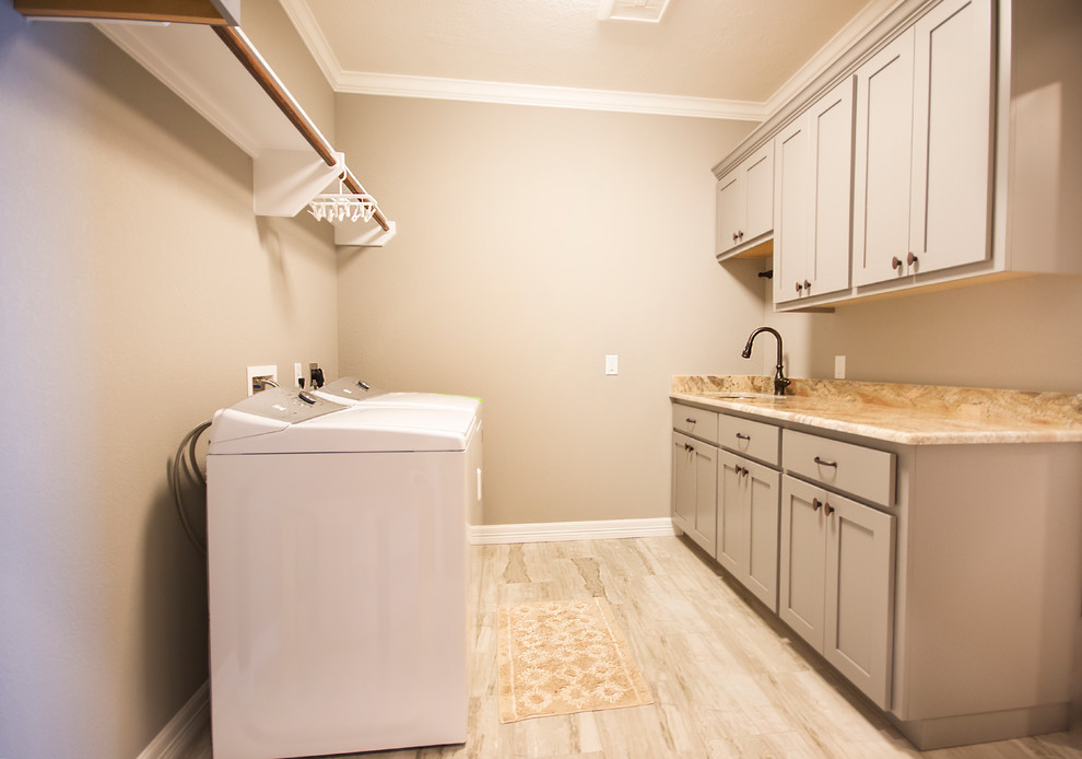 Photo of a transitional l-shaped dedicated laundry room in Austin with an undermount sink, shaker cabinets, beige cabinets, granite benchtops, beige walls, light hardwood floors, a side-by-side washer and dryer and beige benchtop.