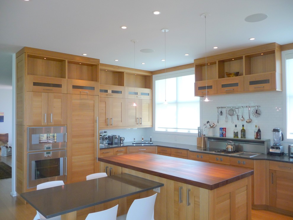 This is an example of a mid-sized modern u-shaped eat-in kitchen in New York with an undermount sink, shaker cabinets, light wood cabinets, white splashback, panelled appliances, light hardwood floors, with island, quartz benchtops and subway tile splashback.