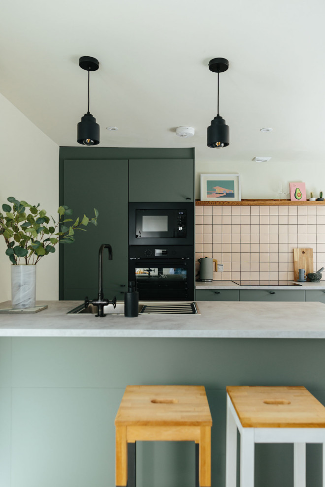 Mittelgroße Moderne Küche mit grünen Schränken, schwarzen Elektrogeräten und Kücheninsel in Dorset