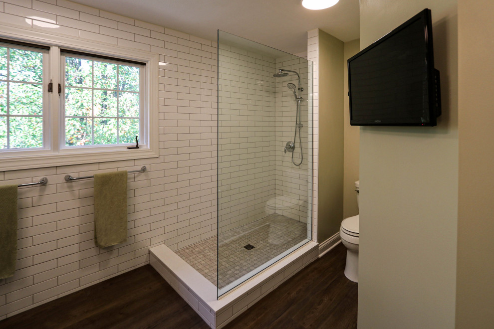 This is an example of a mid-sized transitional master bathroom in Cleveland with flat-panel cabinets, grey cabinets, a corner shower, a two-piece toilet, white tile, green walls, laminate floors, an integrated sink, solid surface benchtops, blue floor, an open shower, beige benchtops, a double vanity and a freestanding vanity.