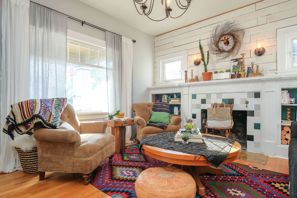 This is an example of an eclectic living room in Portland with white walls, light hardwood floors, a standard fireplace and a tile fireplace surround.