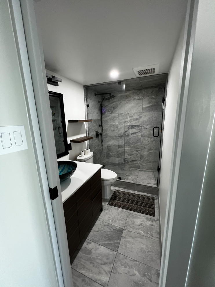 Example of a mid-sized trendy 3/4 white tile and porcelain tile porcelain tile, gray floor and single-sink doorless shower design in Vancouver with black cabinets, a two-piece toilet, white walls, a console sink, quartzite countertops, a hinged shower door, white countertops, a niche and a built-in vanity