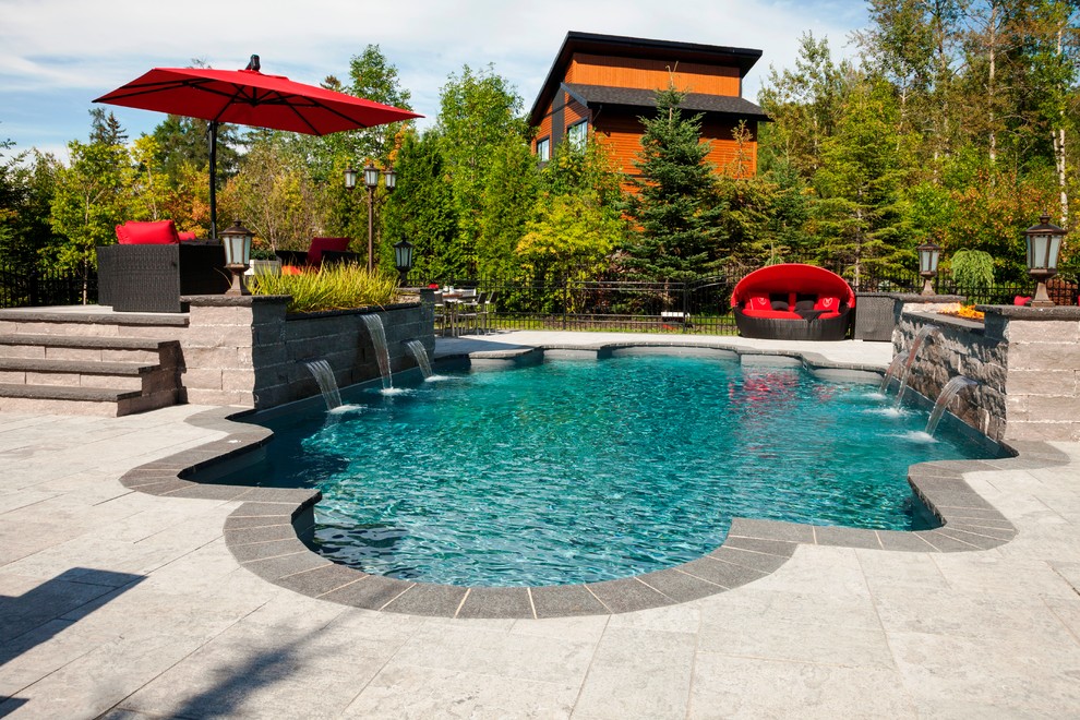 Traditional backyard custom-shaped lap pool in Montreal with a water feature and natural stone pavers.