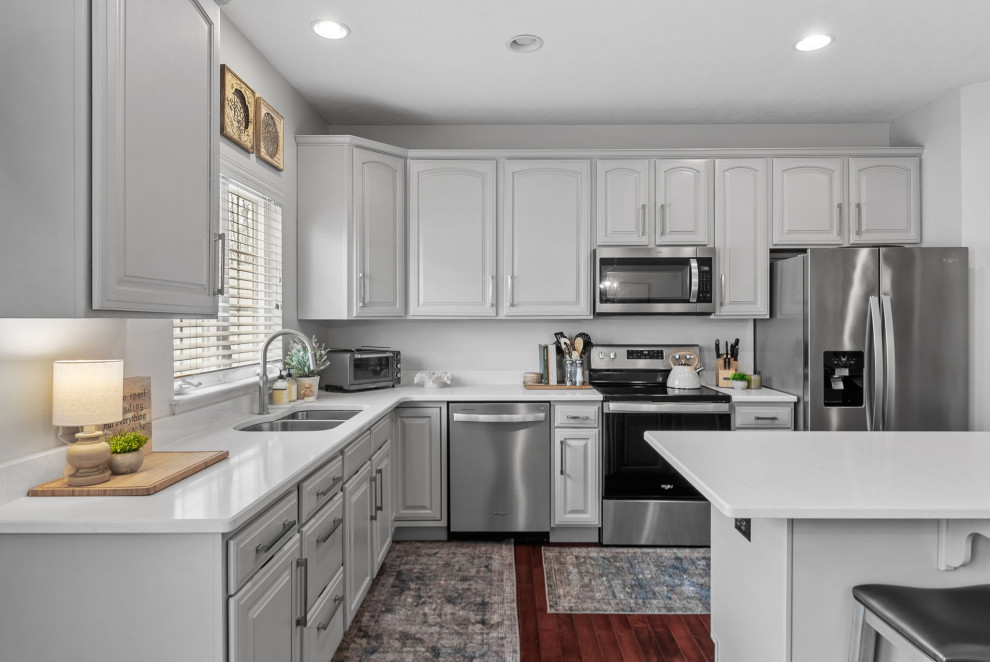 Inspiration for a transitional dark wood floor eat-in kitchen remodel with a double-bowl sink, gray cabinets, quartz countertops, stainless steel appliances, an island and white countertops