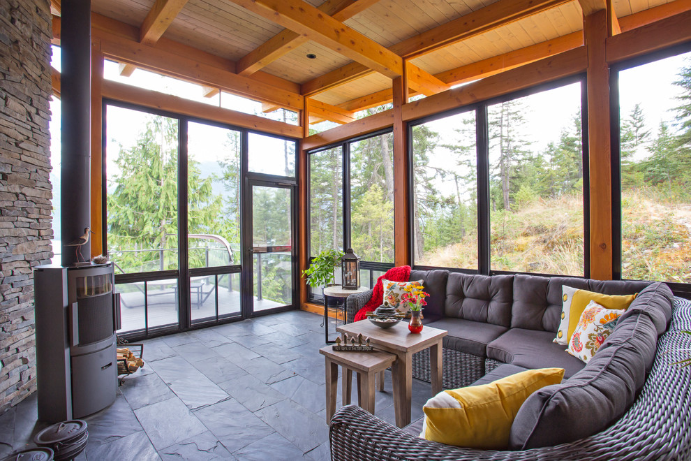 Country sunroom in Vancouver with a wood stove, a metal fireplace surround, a standard ceiling and grey floor.