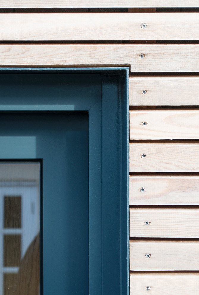 This is an example of a small scandinavian one-storey exterior in London with wood siding and a flat roof.