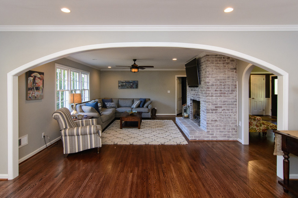 This is an example of a large transitional open concept family room in Birmingham with beige walls, dark hardwood floors, a standard fireplace, a brick fireplace surround and a wall-mounted tv.