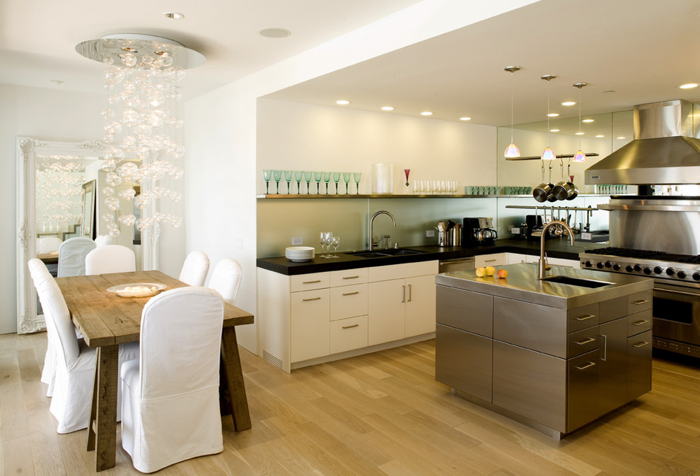 This is an example of a large modern u-shaped open plan kitchen in San Francisco with an undermount sink, flat-panel cabinets, white cabinets, granite benchtops, green splashback, glass sheet splashback, stainless steel appliances, light hardwood floors and with island.