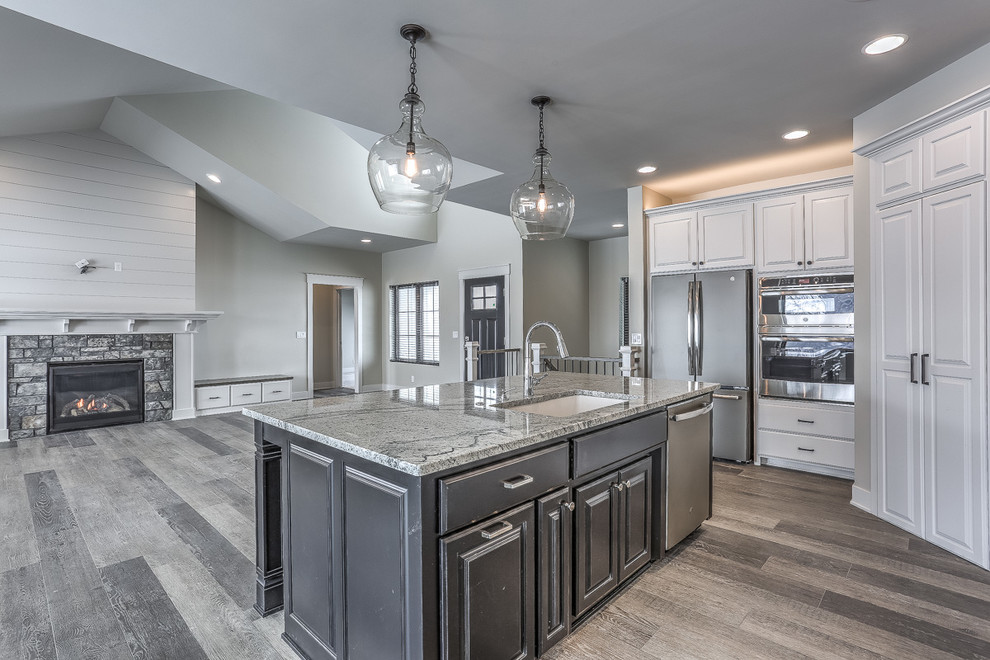 Inspiration for a country l-shaped open plan kitchen in Omaha with an undermount sink, raised-panel cabinets, white cabinets, granite benchtops, white splashback, subway tile splashback, stainless steel appliances, vinyl floors, with island, grey floor and grey benchtop.