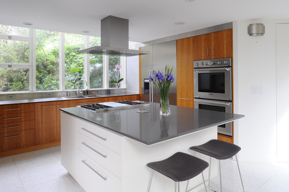 Design ideas for a contemporary kitchen in San Francisco with a double-bowl sink, flat-panel cabinets, medium wood cabinets, stainless steel appliances, porcelain floors, with island and stainless steel benchtops.