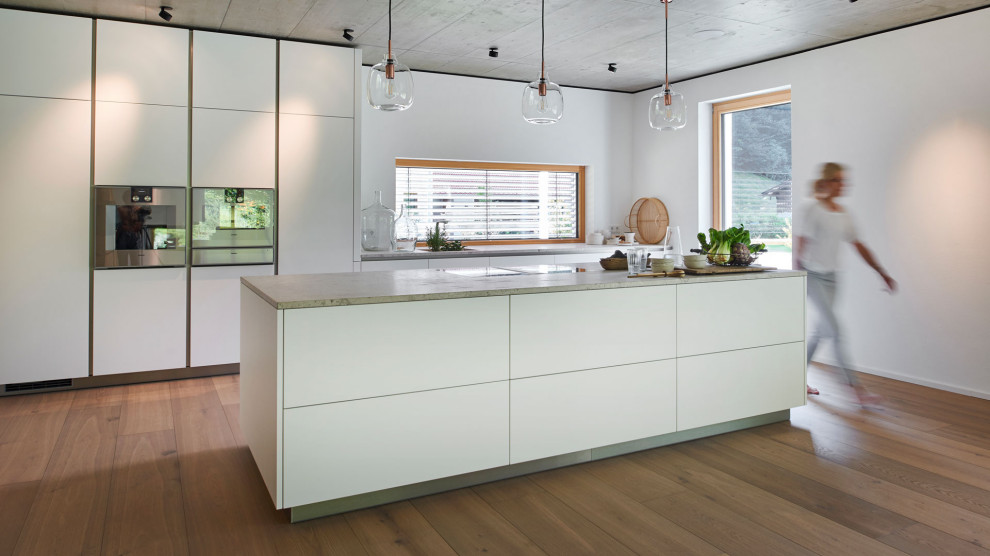Photo of a modern kitchen in Munich with flat-panel cabinets, white cabinets and an island.