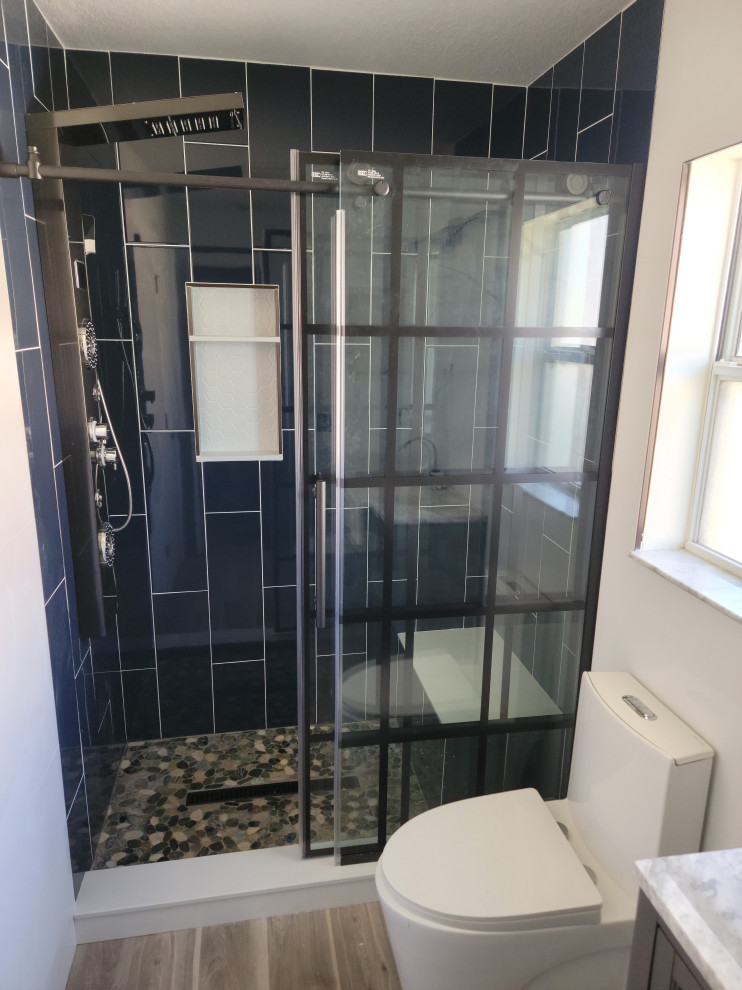 Пример оригинального дизайна: ванная комната в современном стиле с стеклянной плиткой, полом из винила, разноцветным полом, сиденьем для душа, тумбой под одну раковину и кирпичными стенами