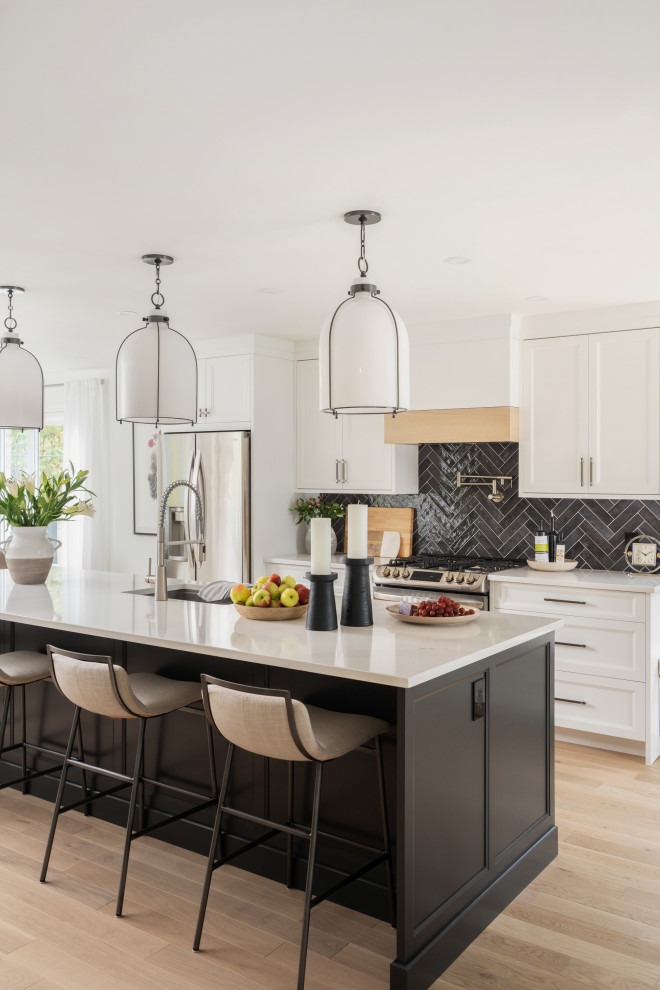 Example of a large transitional single-wall light wood floor and brown floor open concept kitchen design in Montreal with an undermount sink, beaded inset cabinets, white cabinets, quartz countertops, gray backsplash, ceramic backsplash, stainless steel appliances, an island and white countertops