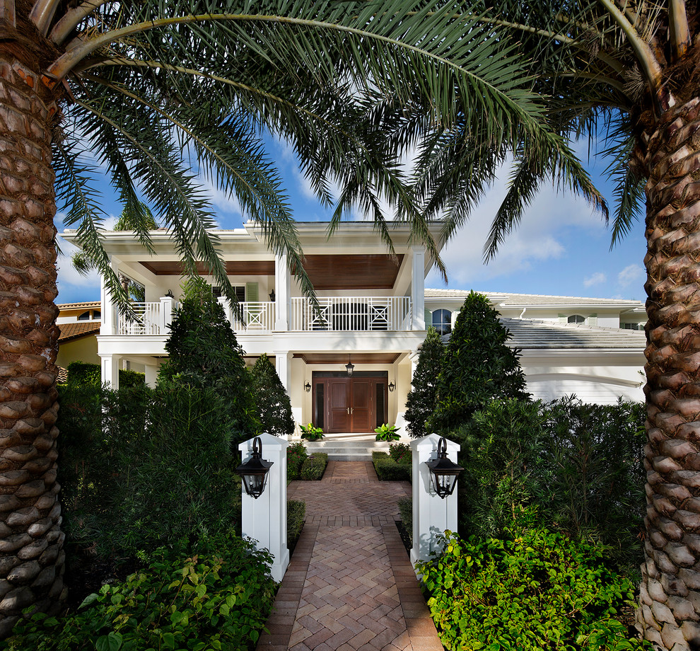 This is an example of a tropical two-storey beige exterior in Miami with a hip roof.