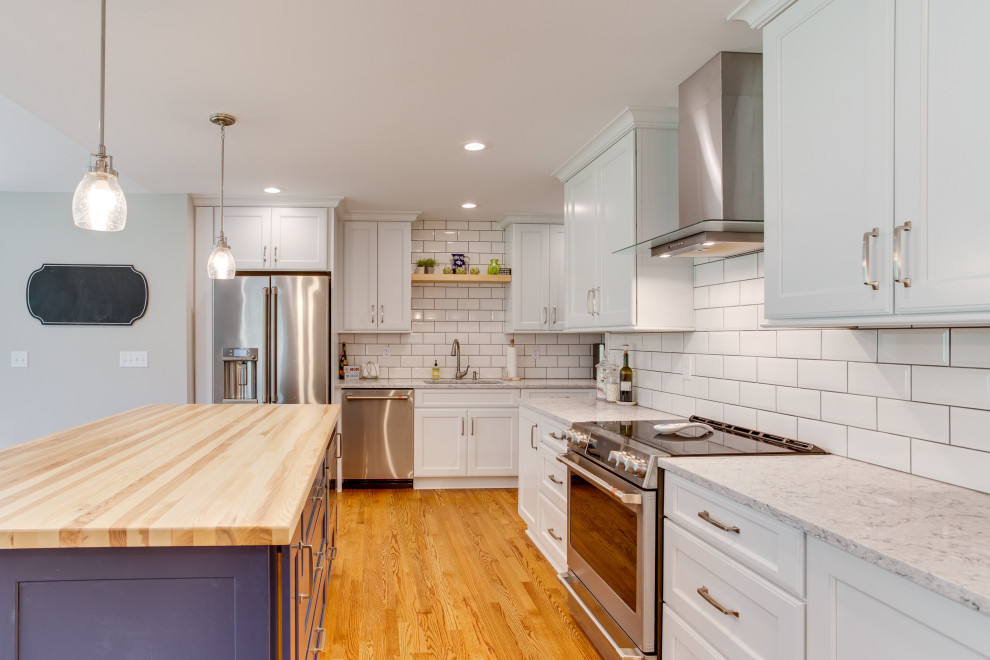 Photo of a large transitional l-shaped eat-in kitchen in Baltimore with an undermount sink, recessed-panel cabinets, quartz benchtops, white splashback, subway tile splashback, stainless steel appliances and with island.