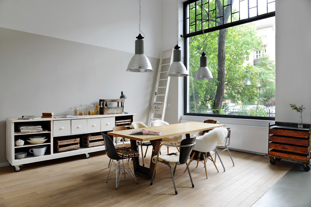 Photo of a large industrial open plan dining in Berlin with white walls, light hardwood floors and no fireplace.