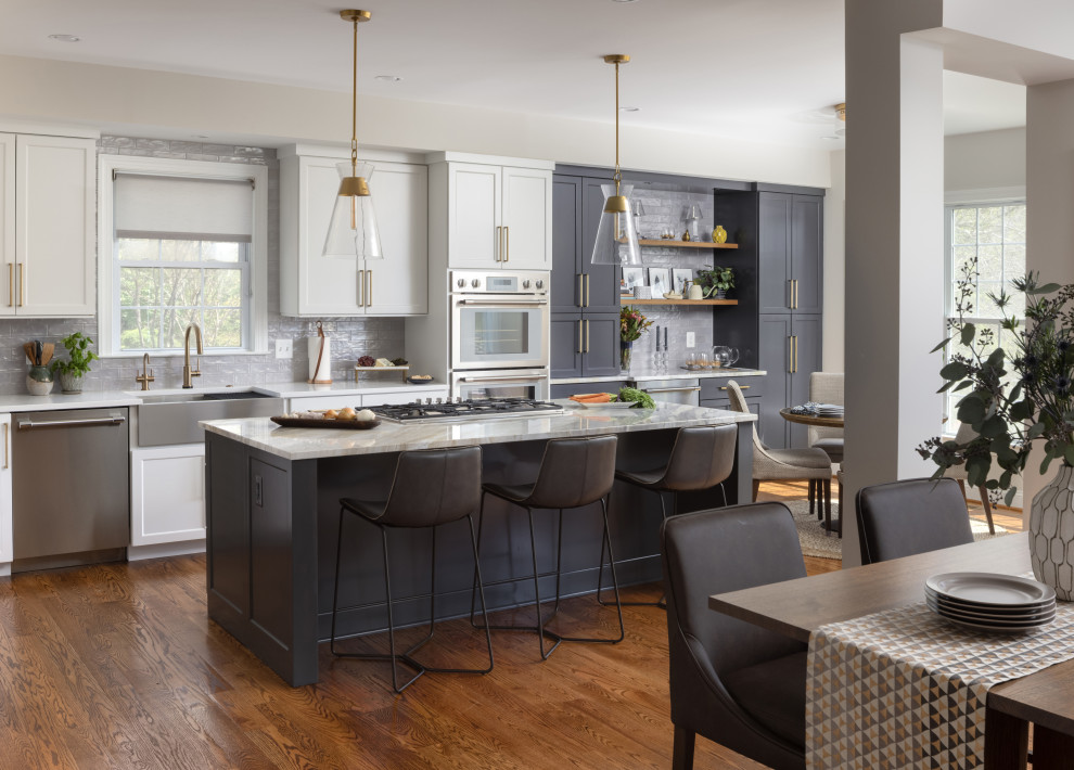 Design ideas for a large transitional l-shaped eat-in kitchen in DC Metro with a farmhouse sink, shaker cabinets, grey cabinets, grey splashback, ceramic splashback, stainless steel appliances, medium hardwood floors, with island, brown floor, grey benchtop and quartzite benchtops.