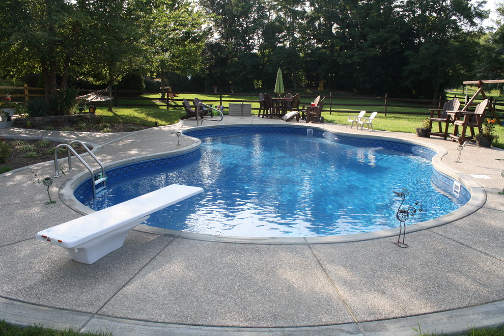 Large backyard concrete and custom-shaped pool photo in Cincinnati