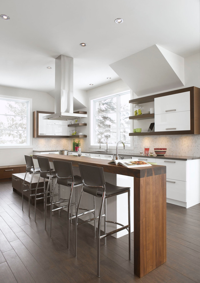 Inspiration for a contemporary kitchen in Montreal with an undermount sink, flat-panel cabinets, white cabinets, stainless steel appliances, dark hardwood floors, wood benchtops, white splashback, mosaic tile splashback and a peninsula.