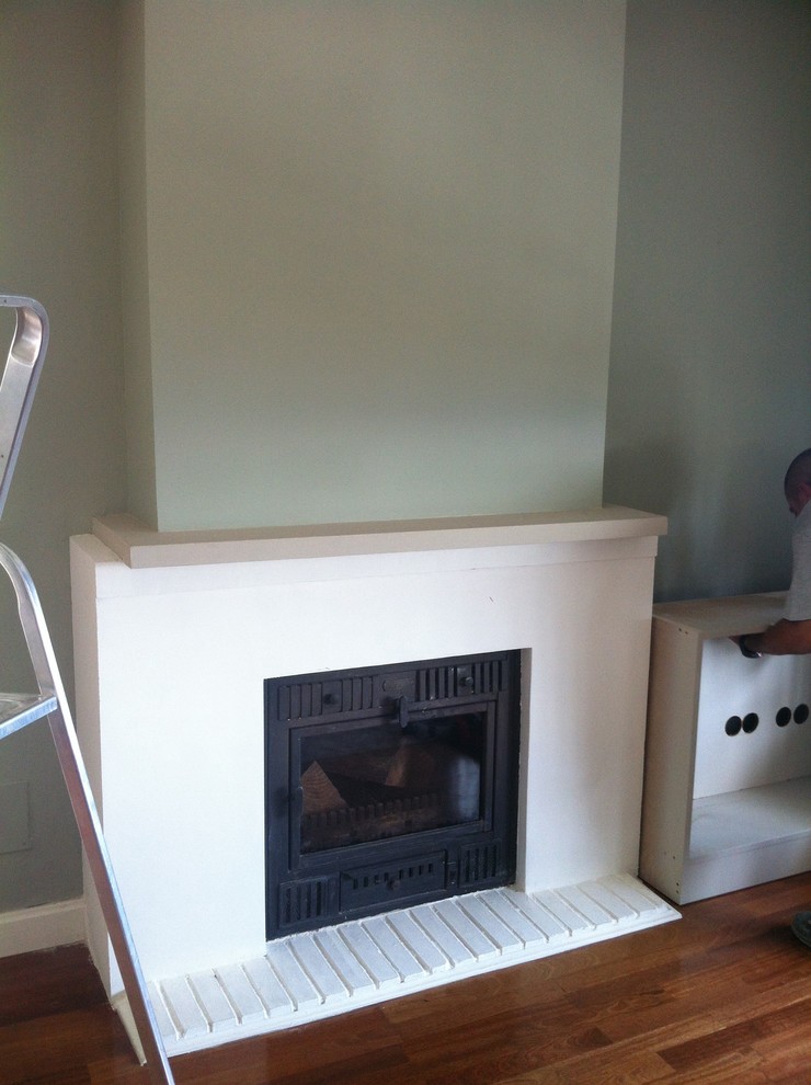 マラガにある小さなエクレクティックスタイルのおしゃれな独立型リビング (ライブラリー、グレーの壁、無垢フローリング、標準型暖炉、漆喰の暖炉まわり) の写真