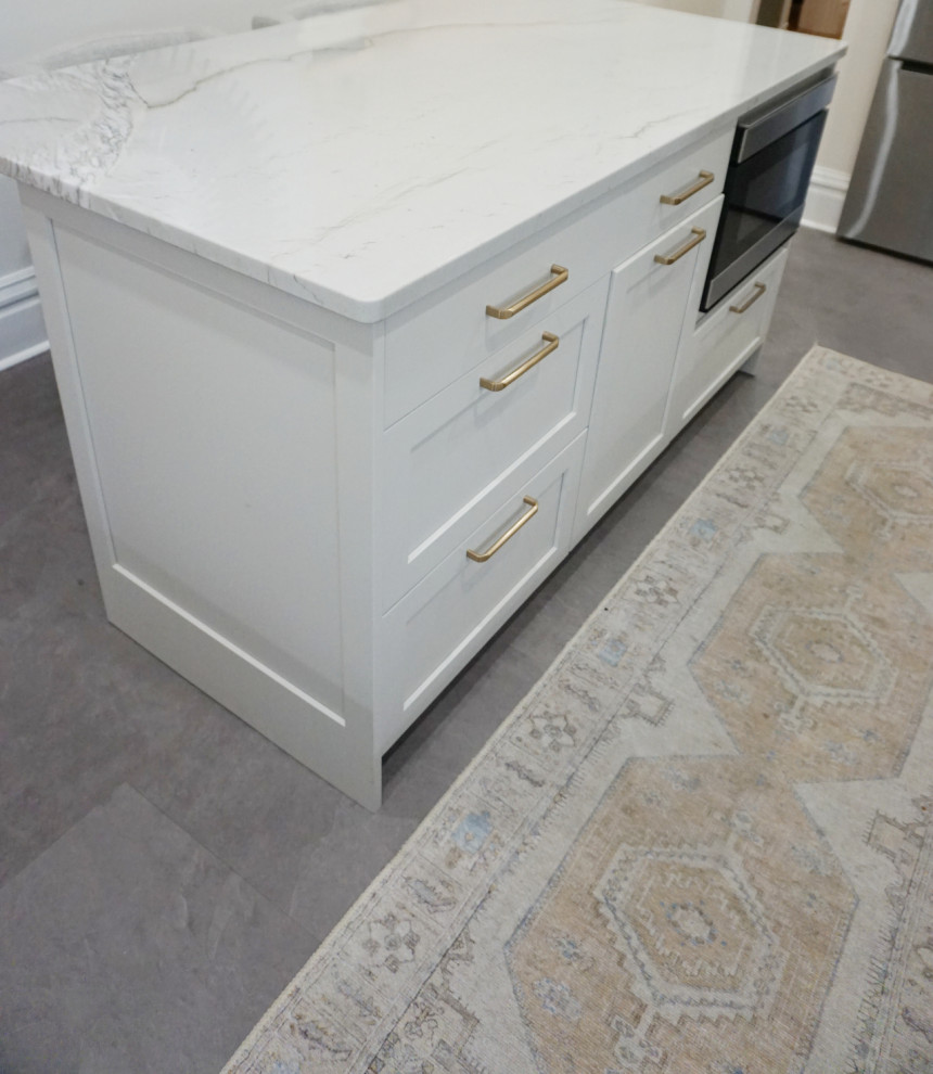 Transitional vinyl floor and gray floor kitchen photo with an undermount sink, shaker cabinets, gray cabinets, quartzite countertops, stone slab backsplash, stainless steel appliances and an island