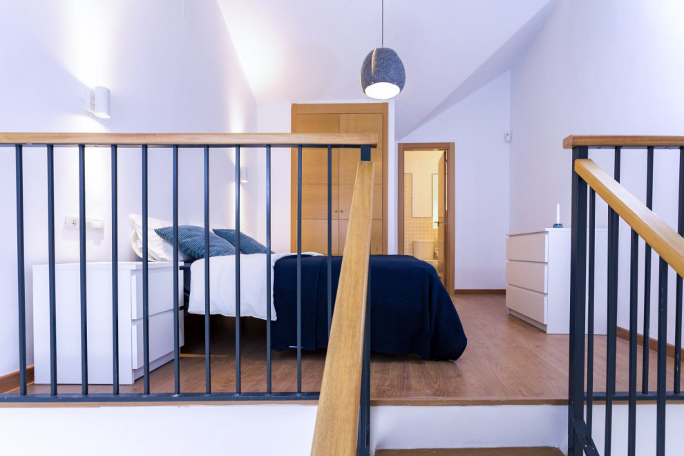 マラガにある小さな北欧スタイルのおしゃれな主寝室 (白い壁、ラミネートの床、勾配天井)