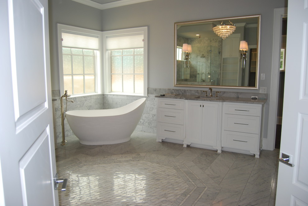 Photo of a large transitional master bathroom in Dallas with shaker cabinets, grey cabinets, a freestanding tub, a corner shower, a one-piece toilet, gray tile, marble, brown walls, dark hardwood floors, a vessel sink, marble benchtops, brown floor and a hinged shower door.